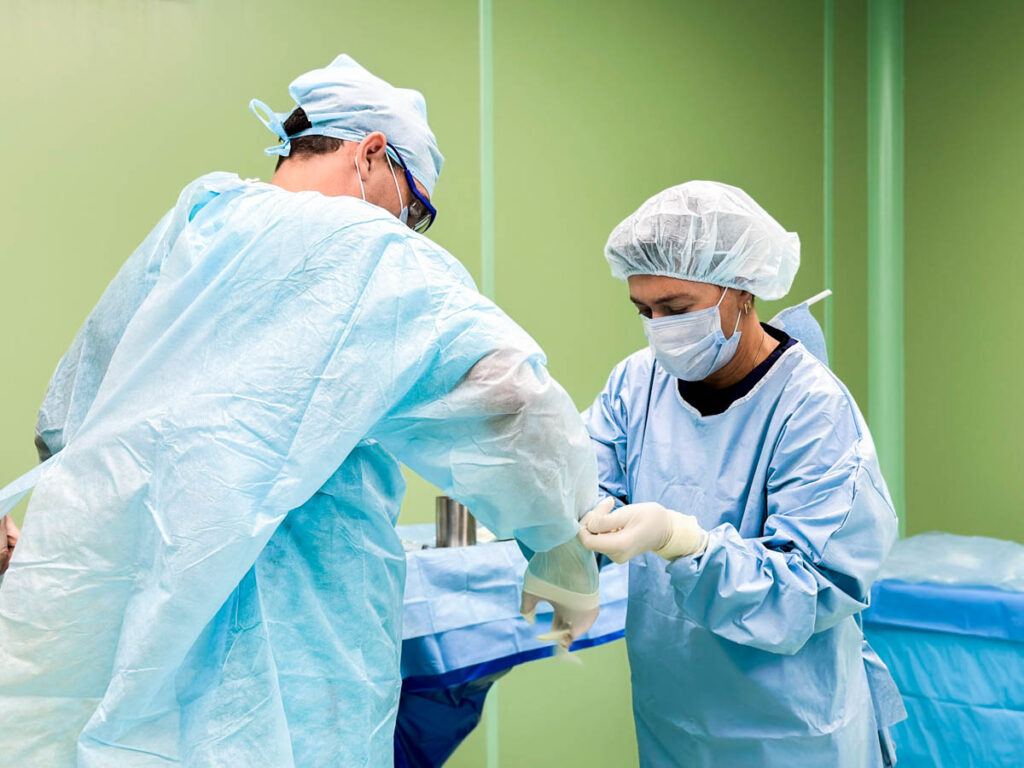Операционная сестра надевает стерильные перчатки врачу. Протезирование полового члена.